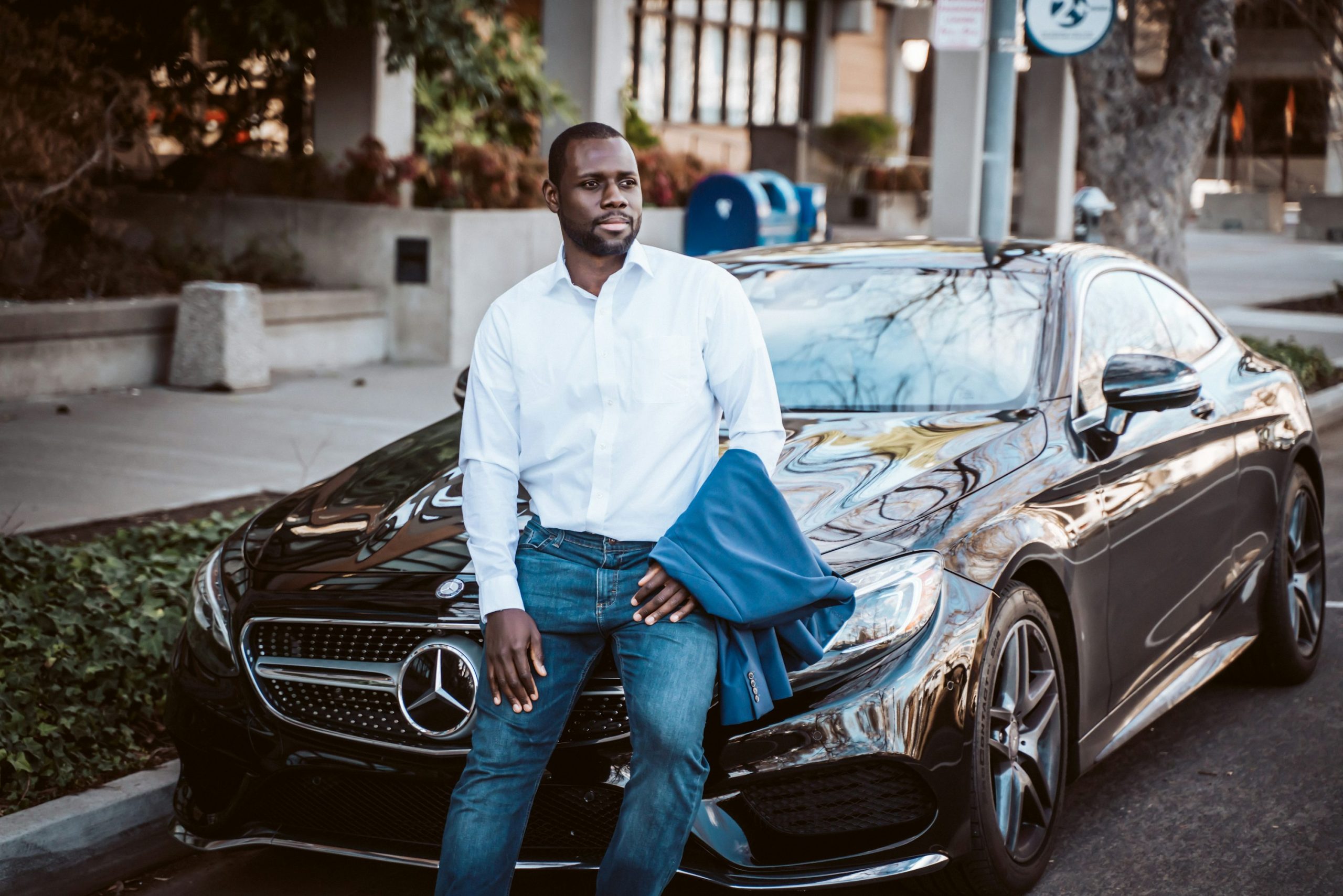 Fortune Vieyra wearing a blue business suit and smiling in front of a Mercedes