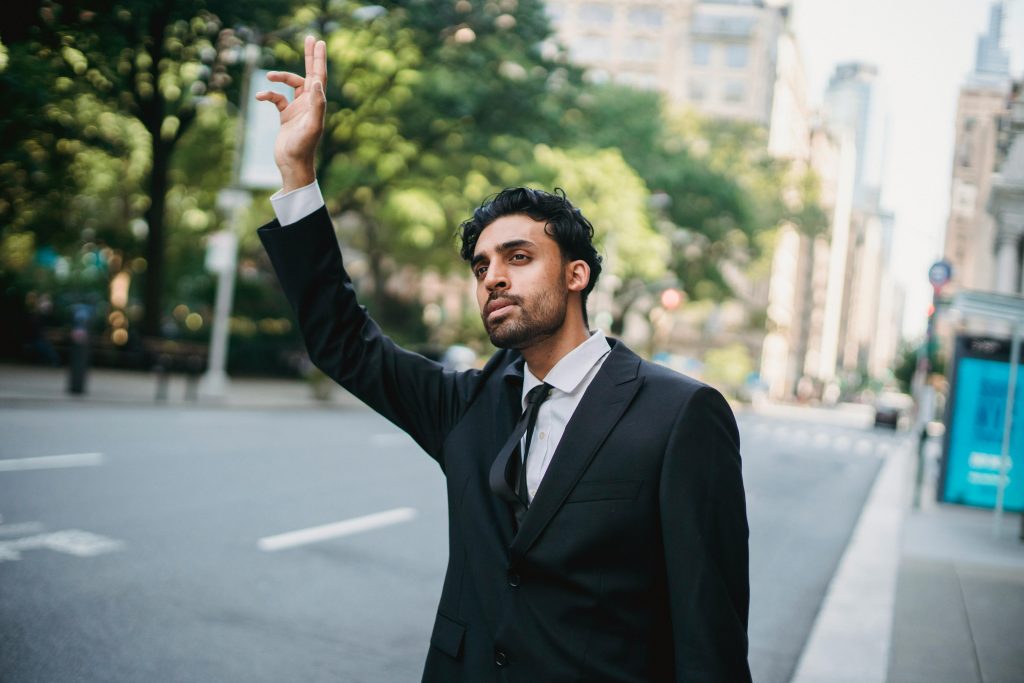 man in black suit jacket standing on sidewalk during daytime