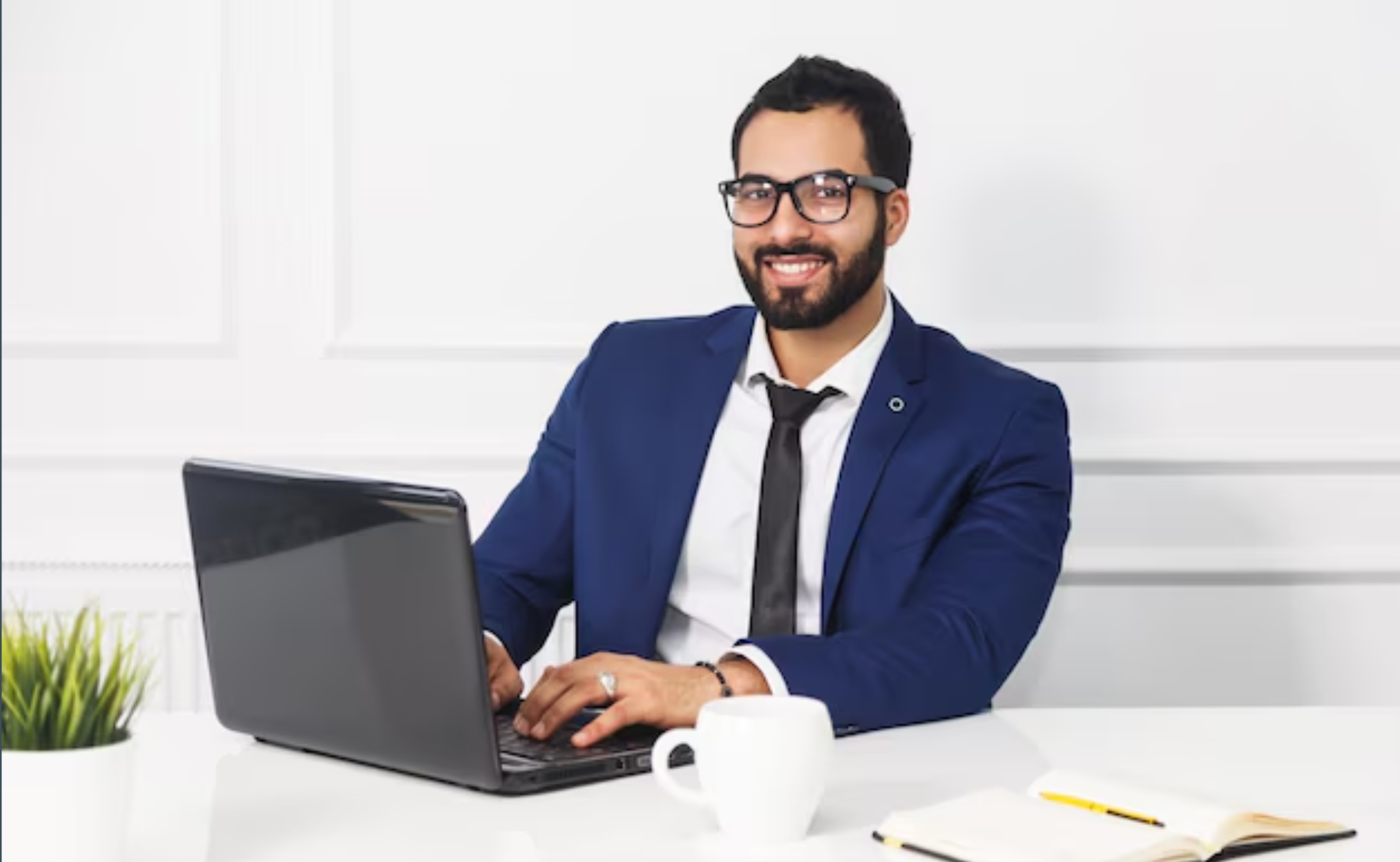 man wearing blue formal suit and eyeglasses sitting and smiling