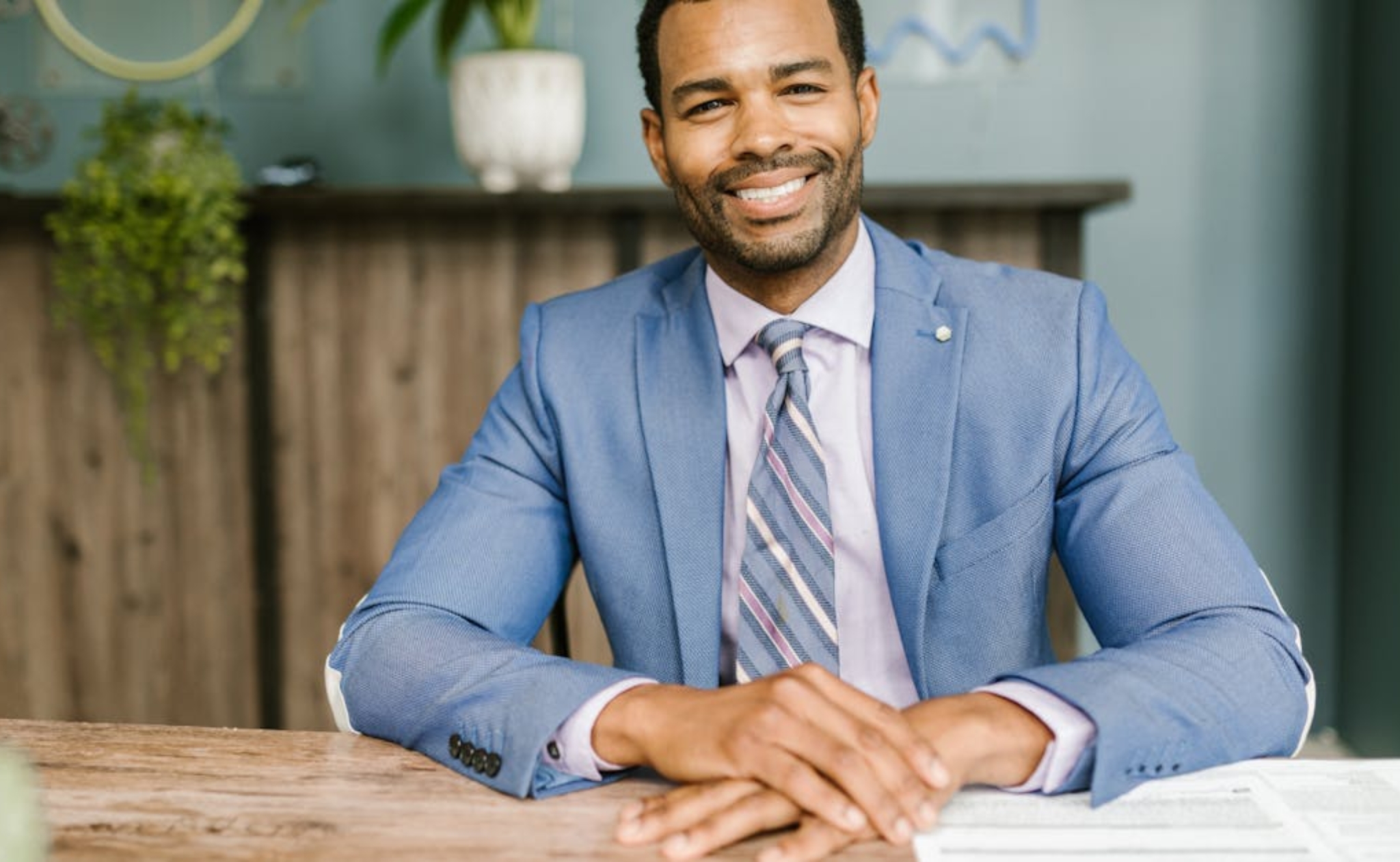 man wearing blue formal suit and glasses sitting and smiling