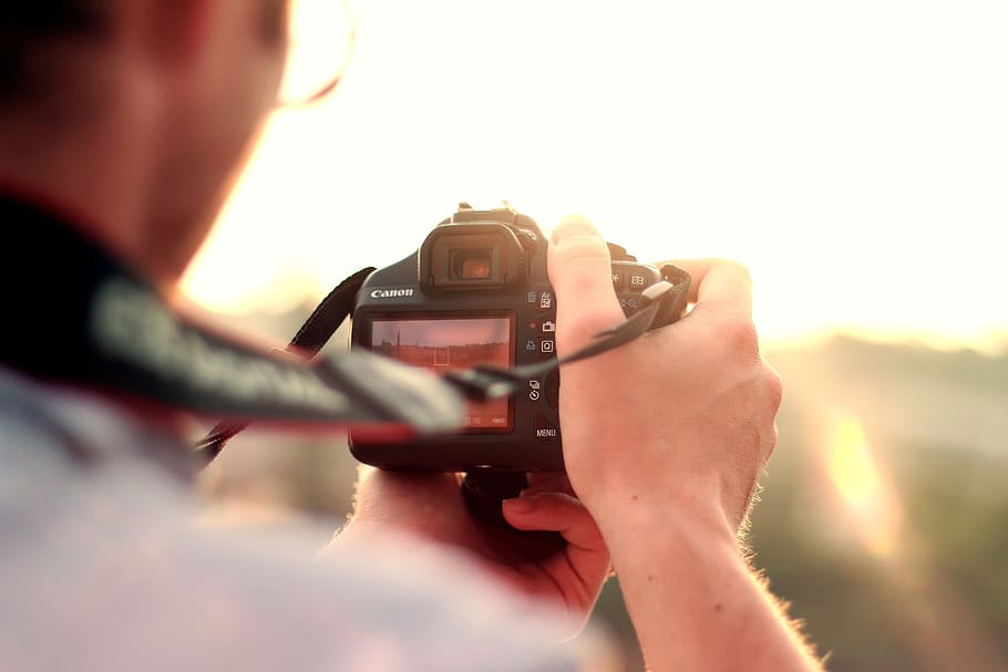 person sitting and looking down near black DSLR camera