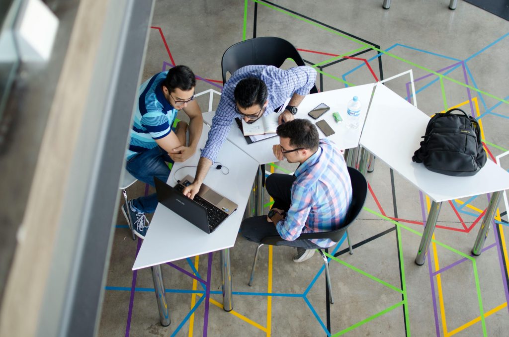 Top view photo of 3 men in front of laptop