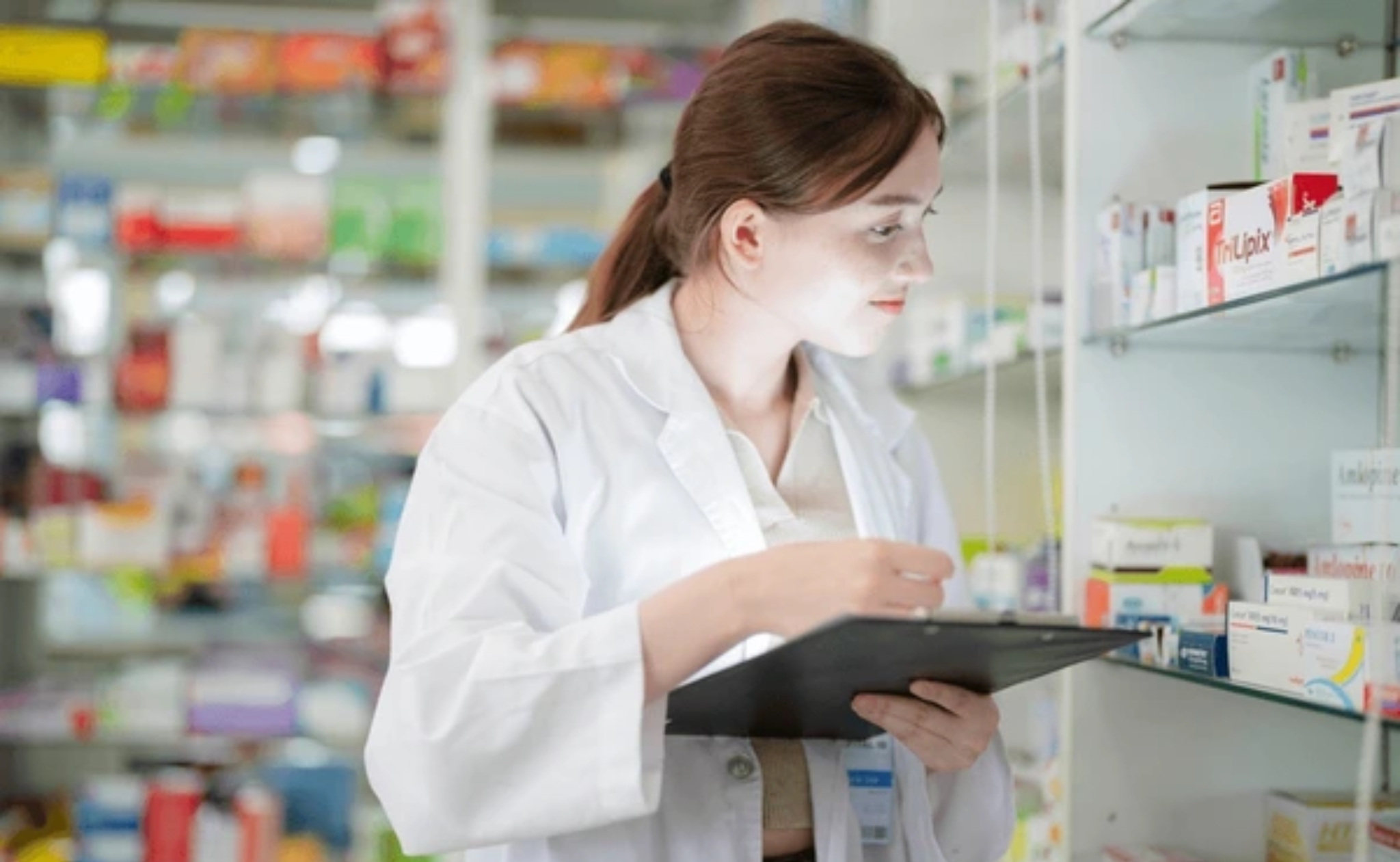 A female pharmacist is selecting a drug from the pharmacy inventory.